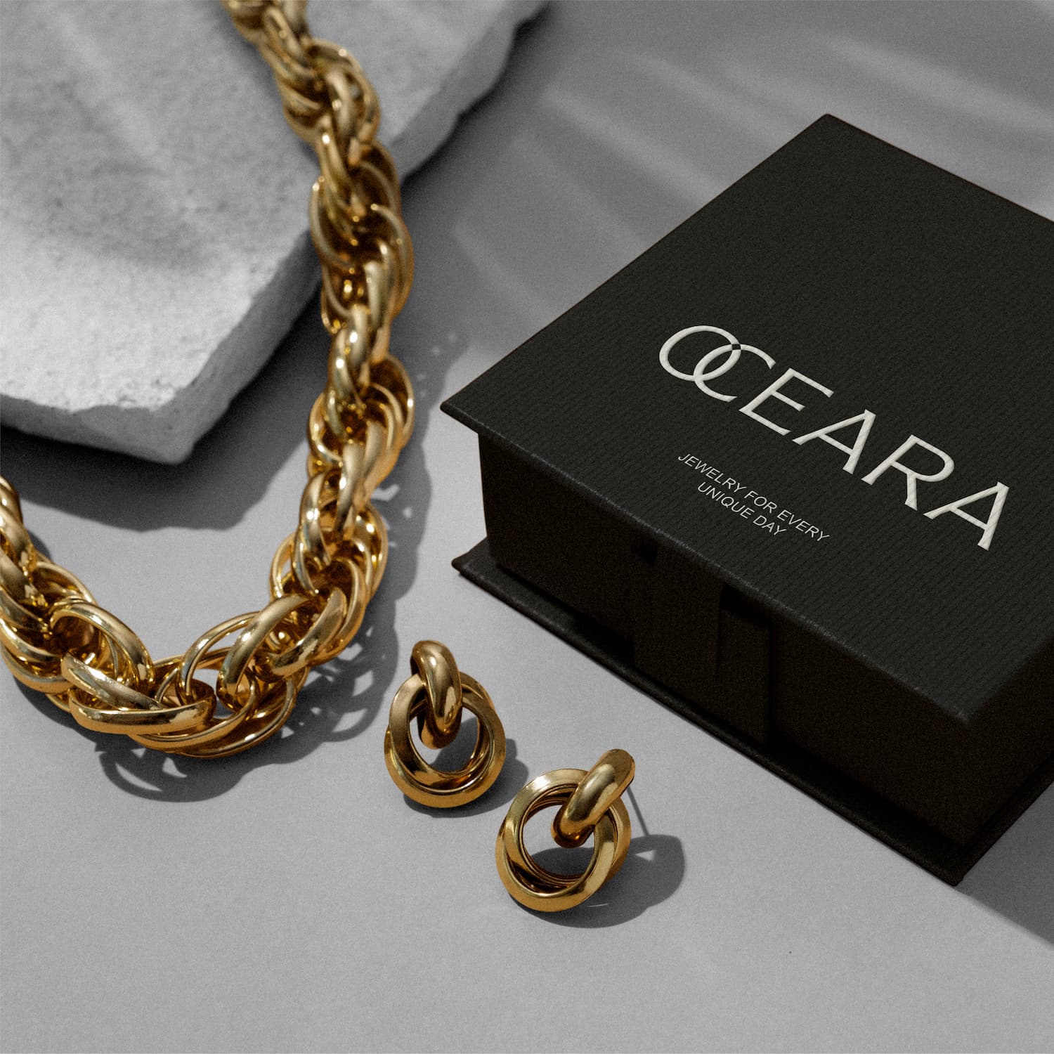 Jewelry packaging design for OCEARA, including a black branded box and gold chain with matching earrings. Designed for product photography and brand visuals. Designed byannas.com.