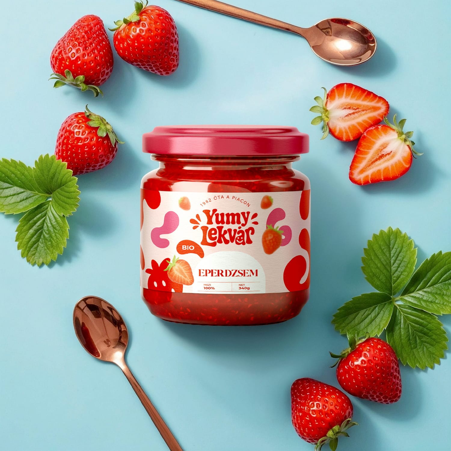Yumy Lekvár strawberry jam jar with fresh strawberries, mint leaves and copper spoons on a blue background: label design by byannas